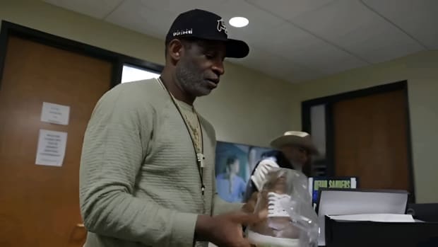 Deion Sanders holding a Taft gator shoe at CU